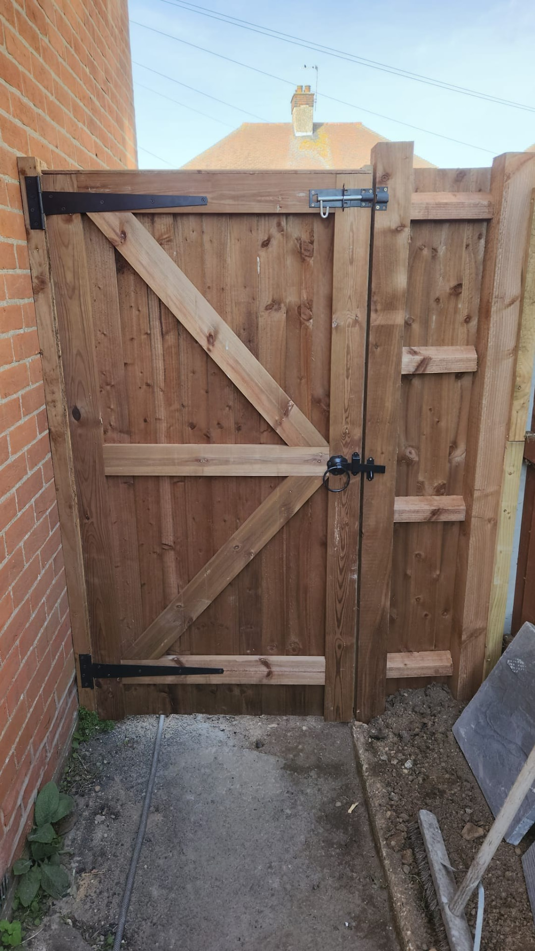 Braced timber garden gate with black metal latch and hinges viewed from inside