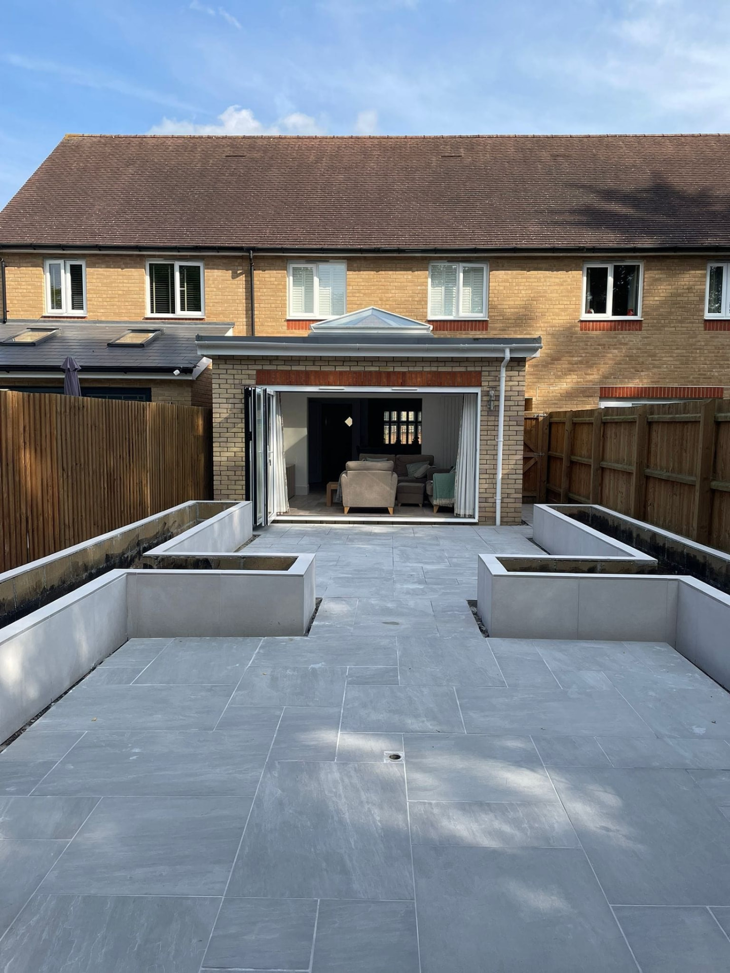 Raised beds edging a paved garden area, built to give the planting structure