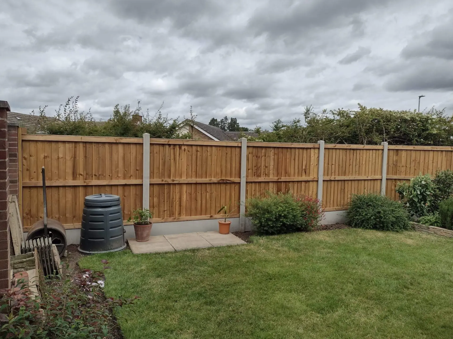 New close-board timber fence panels with concrete posts and gravel boards along a lawned garden boundary