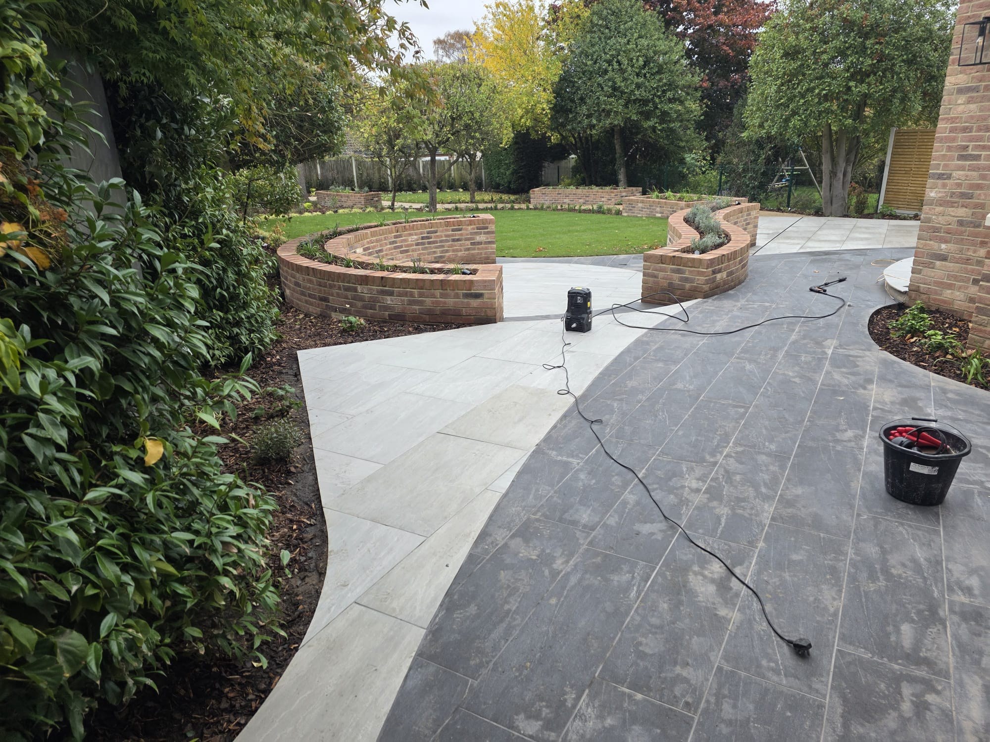 Paved patio with curved brick planter walls opening onto a lawn
