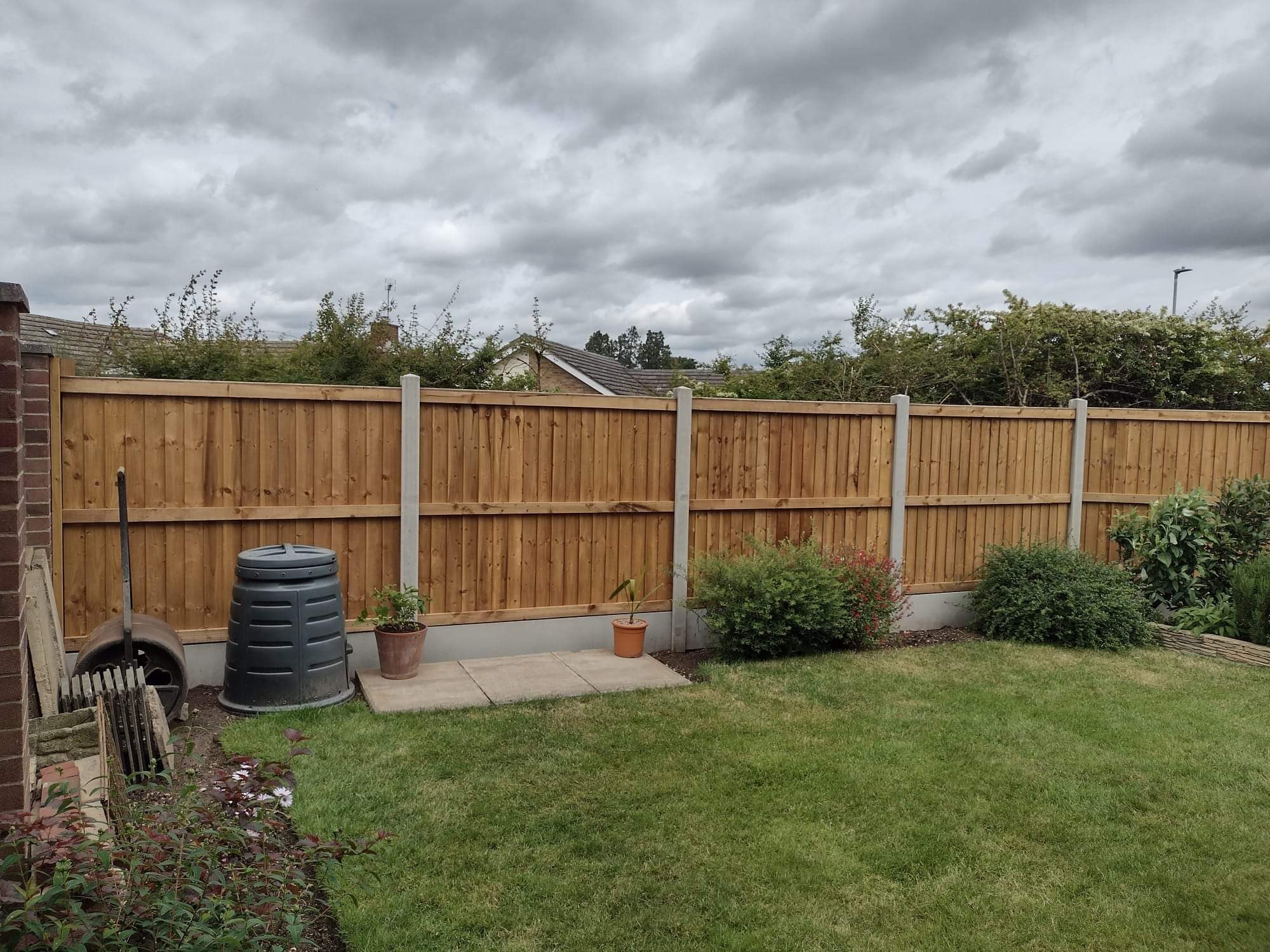New timber fence run bordering a lawn with concrete posts set solid