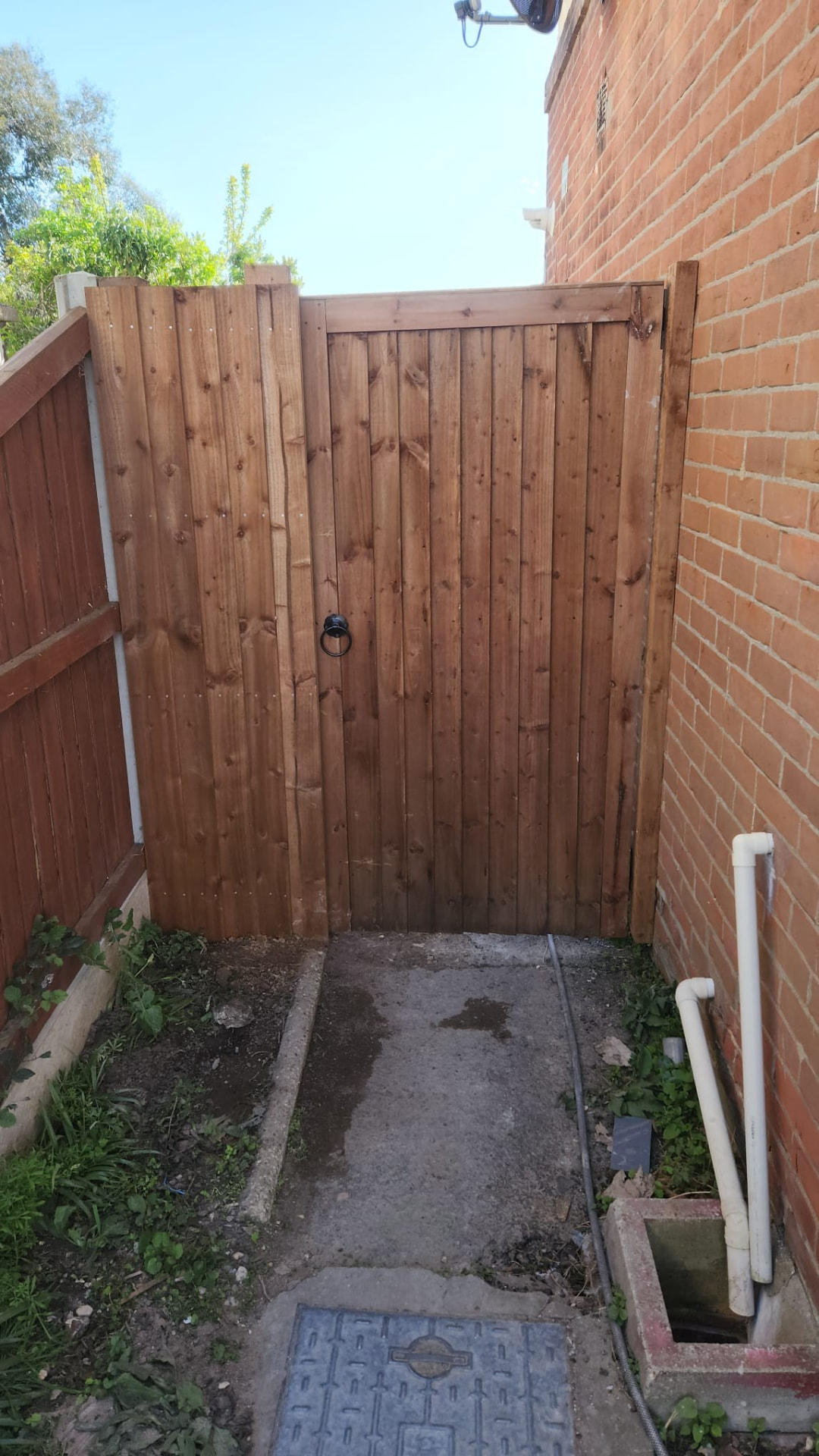 New timber pedestrian garden gate hung between a brick wall and fence