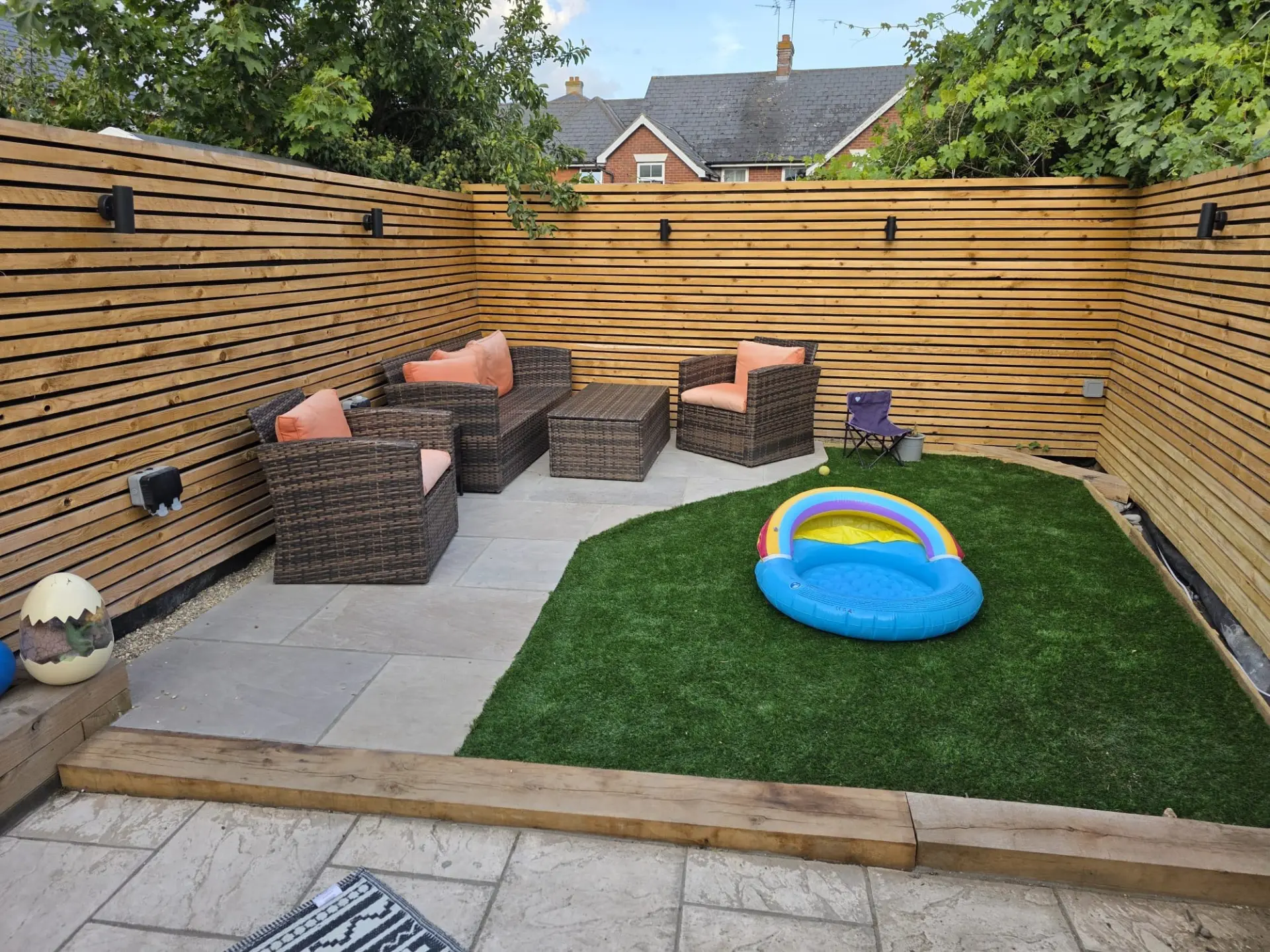 Artificial grass lawn with sleeper edging, porcelain paving and modern slatted timber fencing