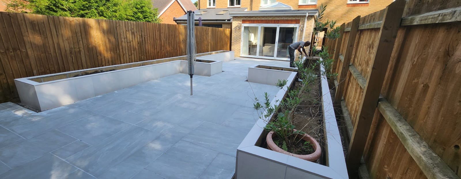 Wide grey porcelain patio with rendered raised planters in a new Essex garden